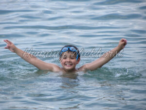 Fröhlich im Wasser schwimmender Junge - ImageShop
