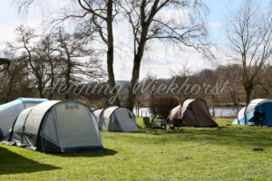 Zeltlager auf der Wiese an einem Flussufer - ImageShop